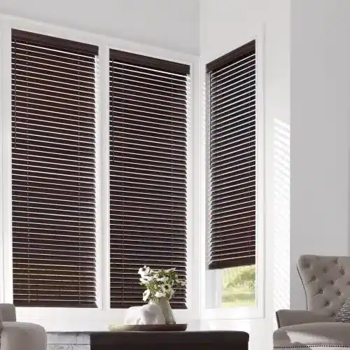 Dark brown window blinds with horizontal slats in a modern home interior. Bright sunlight filters through, highlighting the sleek design and cozy living space ambiance.