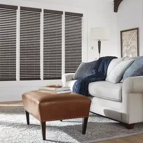 Elegant white sofa with assorted cushions and a navy throw blanket, complemented by a modern floor lamp and stylish framed artwork, creating a warm and inviting living space.
