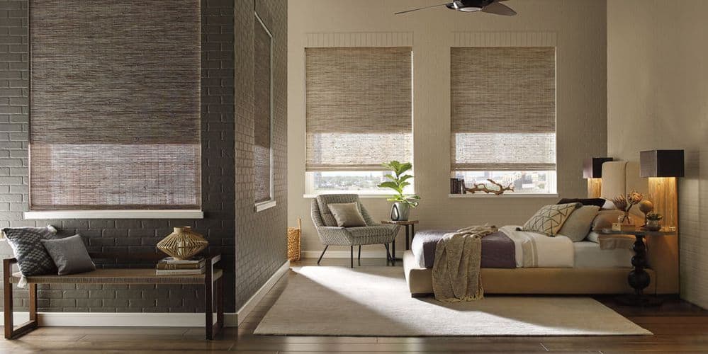 Bright and airy bedroom featuring a large bed, comfortable seating, and beautifully textured window coverings for a relaxing ambiance.