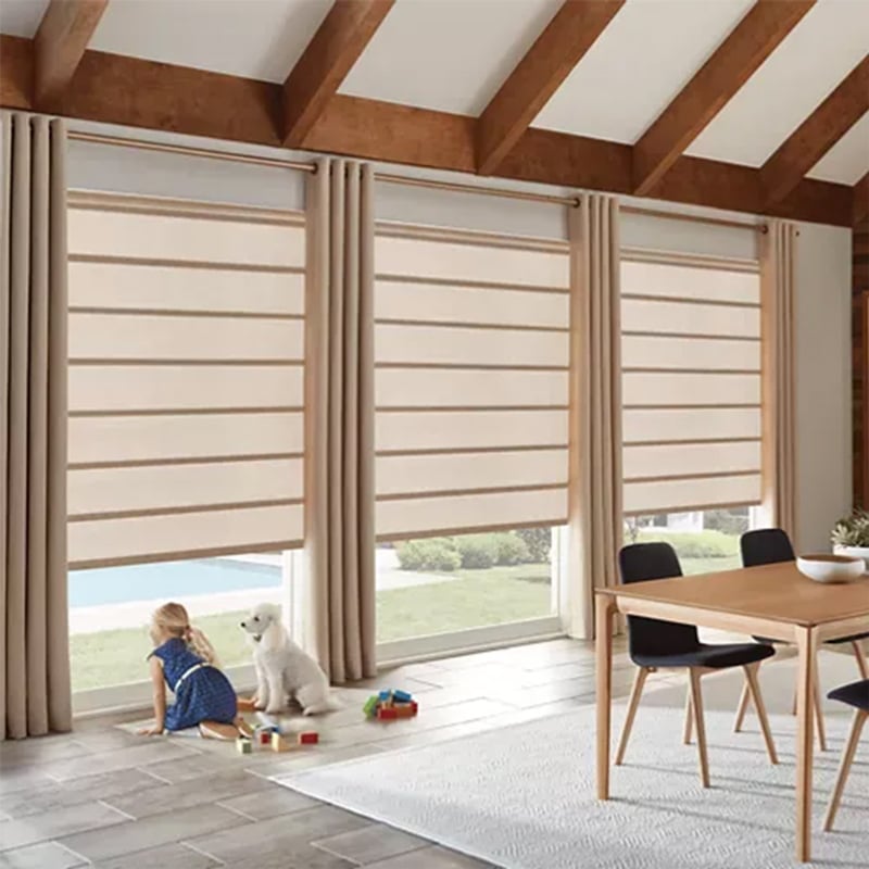 Bright interior featuring large windows with beige Roman shades, a wooden dining table with black chairs, and a girl with her dog playing by the window.