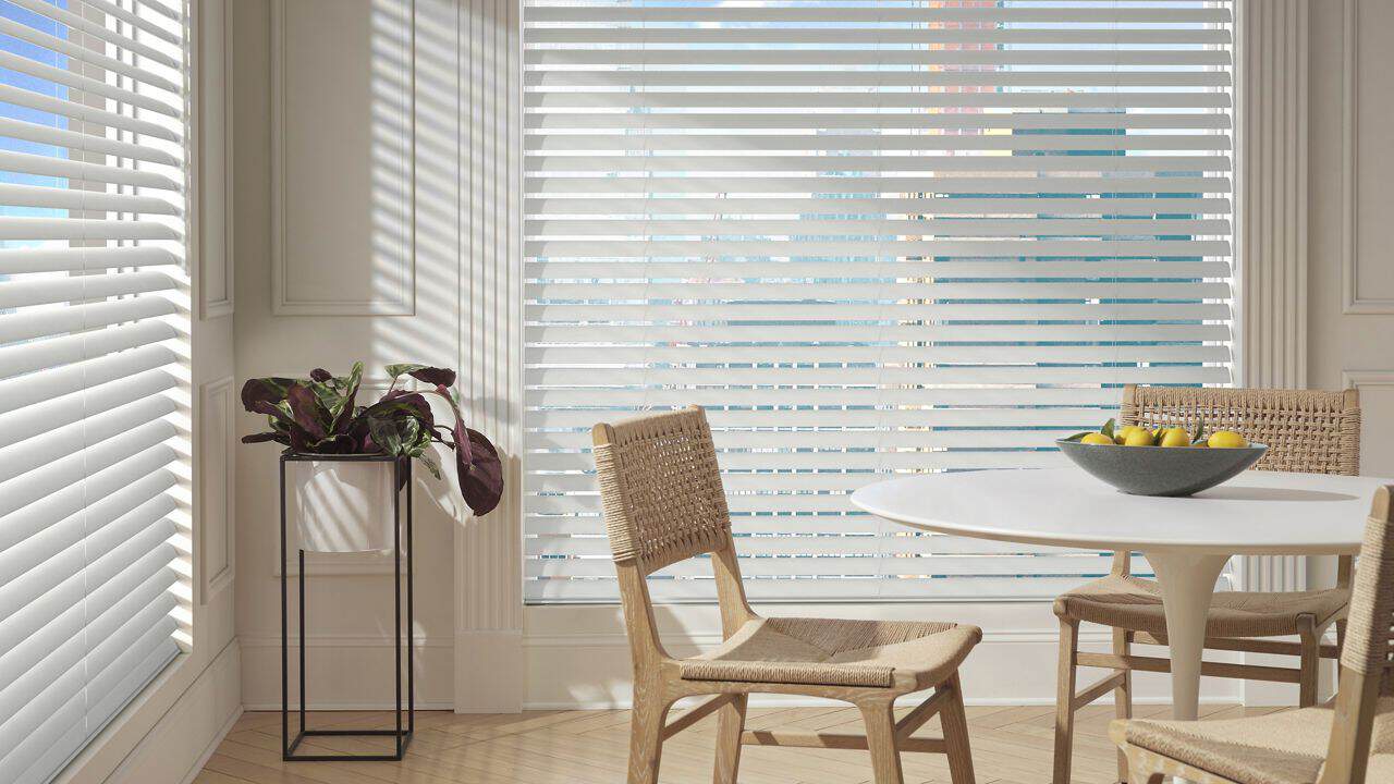 Bright living room with white window blinds and wooden floors.