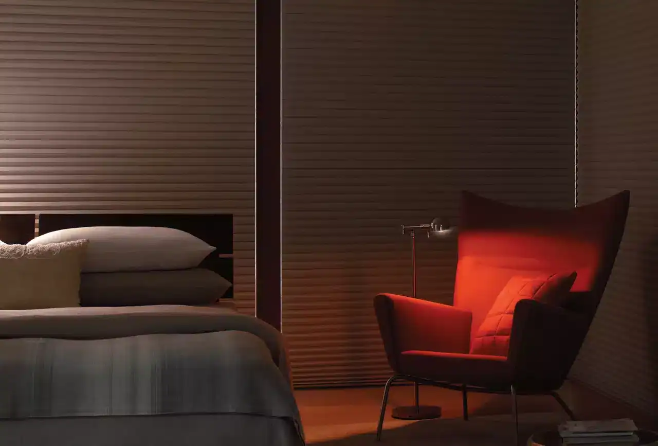 A stylish bedroom featuring a comfortable bed and a cozy, modern reading chair illuminated by a warm red light, perfect for relaxation and leisure.