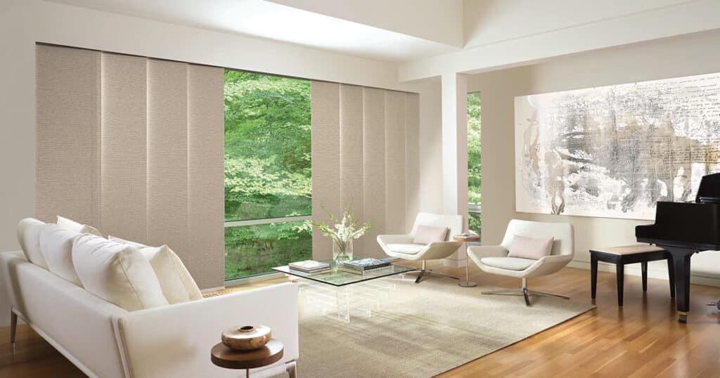 Bright interior featuring contemporary white sofas and sleek black grand piano, filled with natural light from expansive windows overlooking green trees, accented with minimalist decor and abstract artwork.