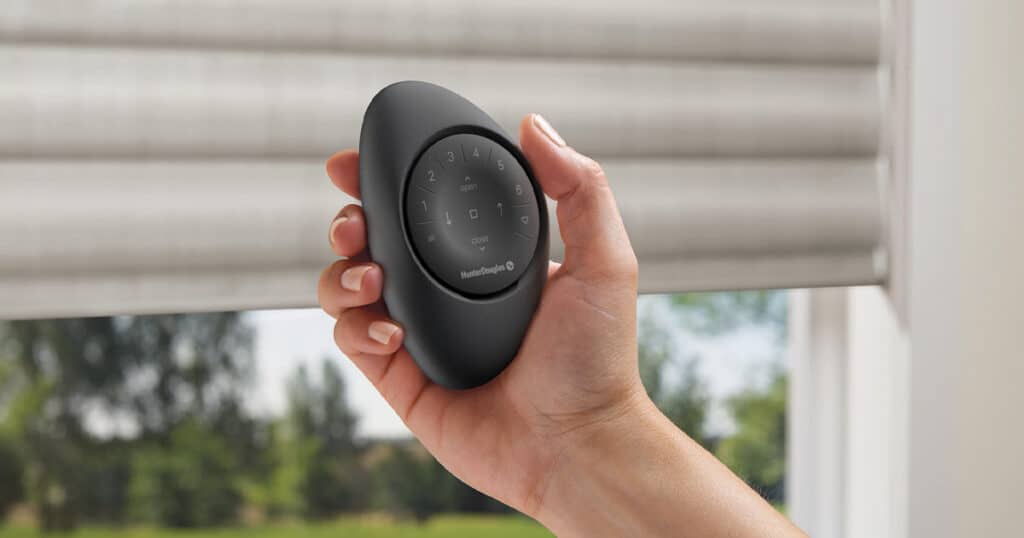 Wireless smart door lock remote with keypad and app access, hand-held security remote for home and office door security, Hunter Douglas window blinds in background.