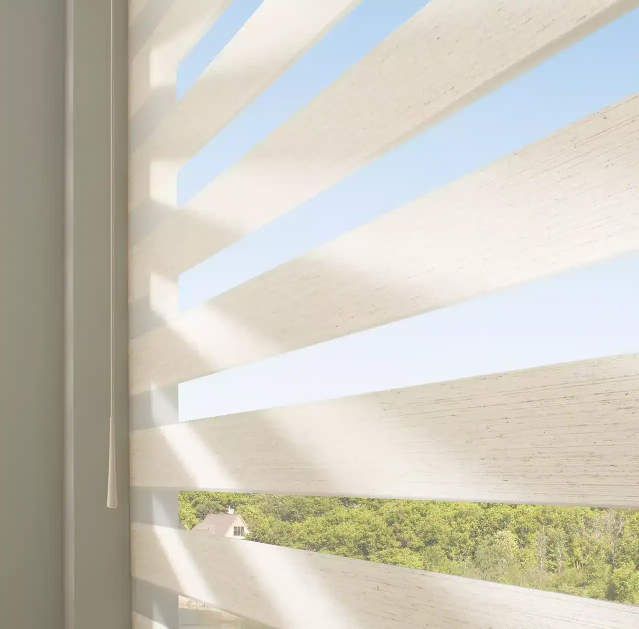 Bright sunlight filters through white horizontal window blinds, creating patterns of light and shadow, with a view of lush greenery outside.