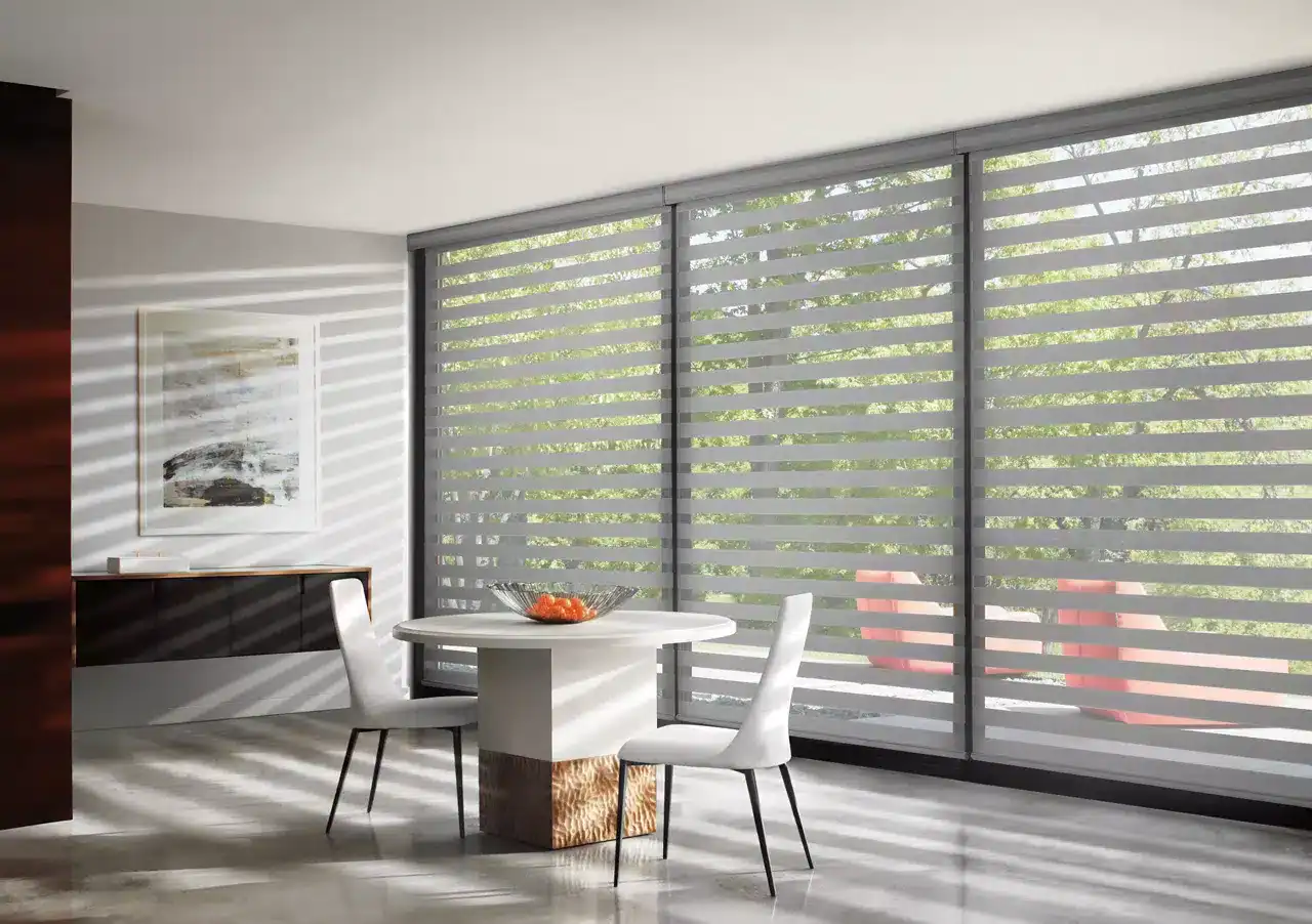 Bright, modern dining space with elegant zebra blinds on large glass sliding doors, enhancing natural light and privacy. Minimalist decor with white table and chairs, perfect for contemporary homes.