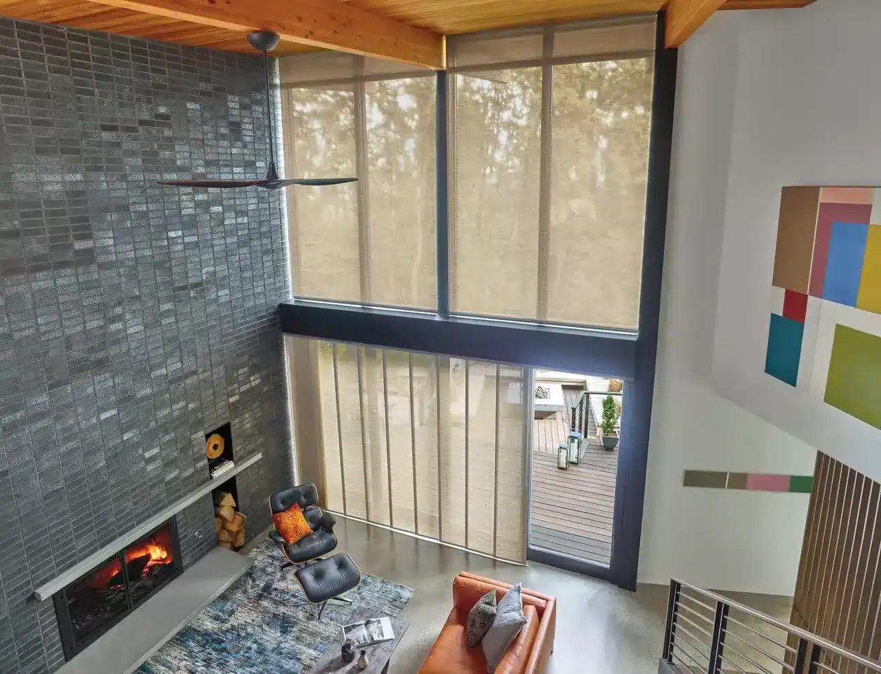Spacious living area with tall windows, fireplace, and modern furniture highlighting contemporary home interior design. Bright natural light, high ceiling, and stylish decor create a welcoming atmosphere.