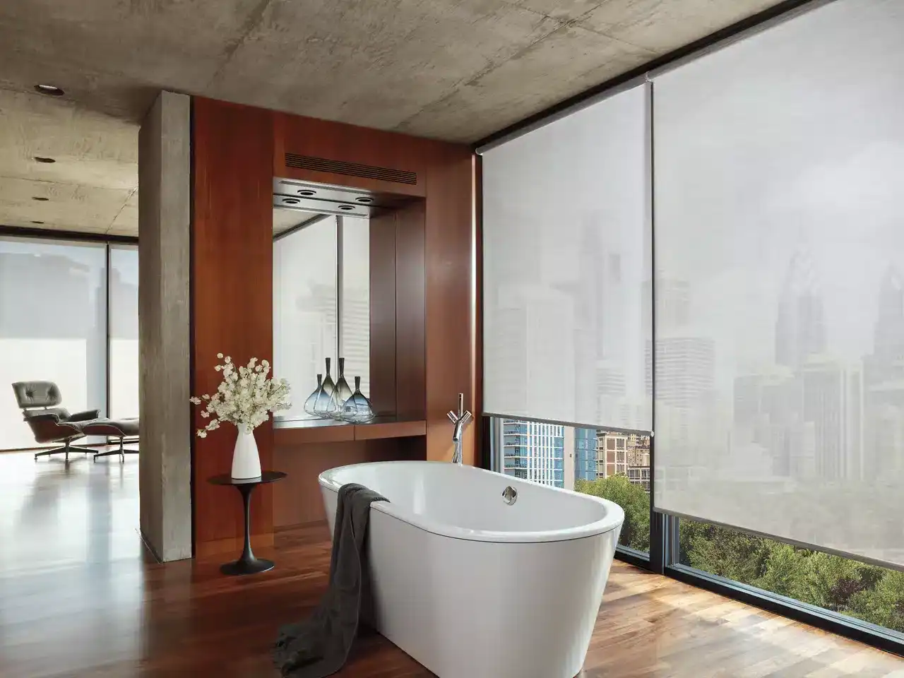 Bright and luxurious bathroom with freestanding bathtub and city skyline views, wooden flooring, decorative vases, and minimalist decor in urban high-rise living space.