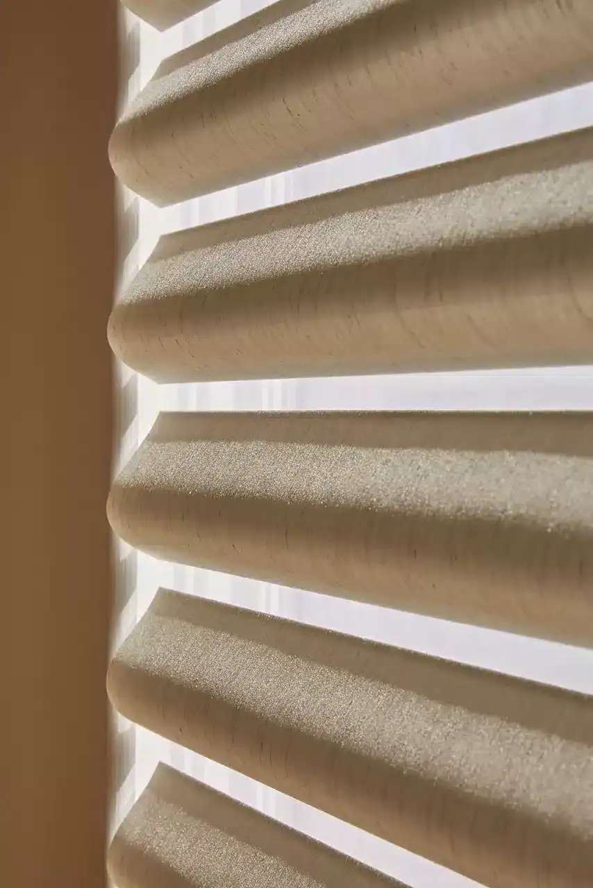 Wooden blinds with horizontal slats, natural beige color, close-up view, modern window covering, light filtering through, interior decor element, smooth texture, stylish home design, contemporary window treatment, minimalistic aesthetic.