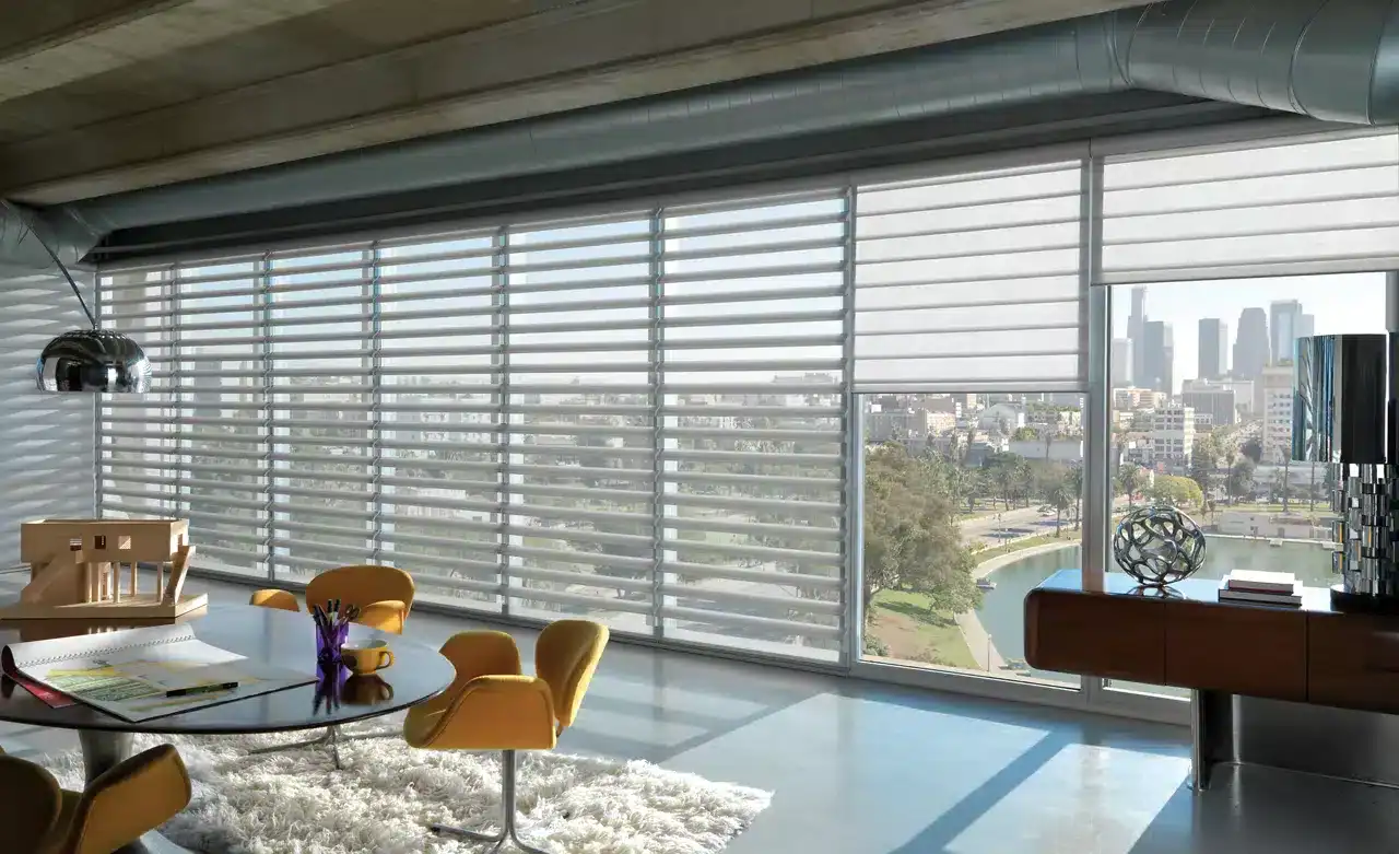Modern office space with large windows and adjustable blinds overlooking a city skyline and park, bright natural lighting, stylish furniture, and contemporary decor.