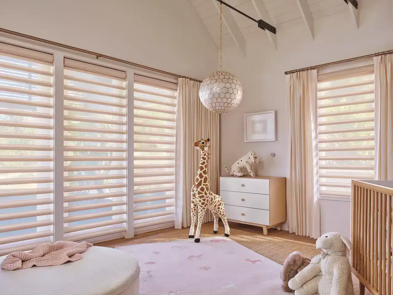 Bright nursery with plush toys, stuffed giraffe, dog, and rabbit in a cozy, sunlit room with modern window shades and calming decor.