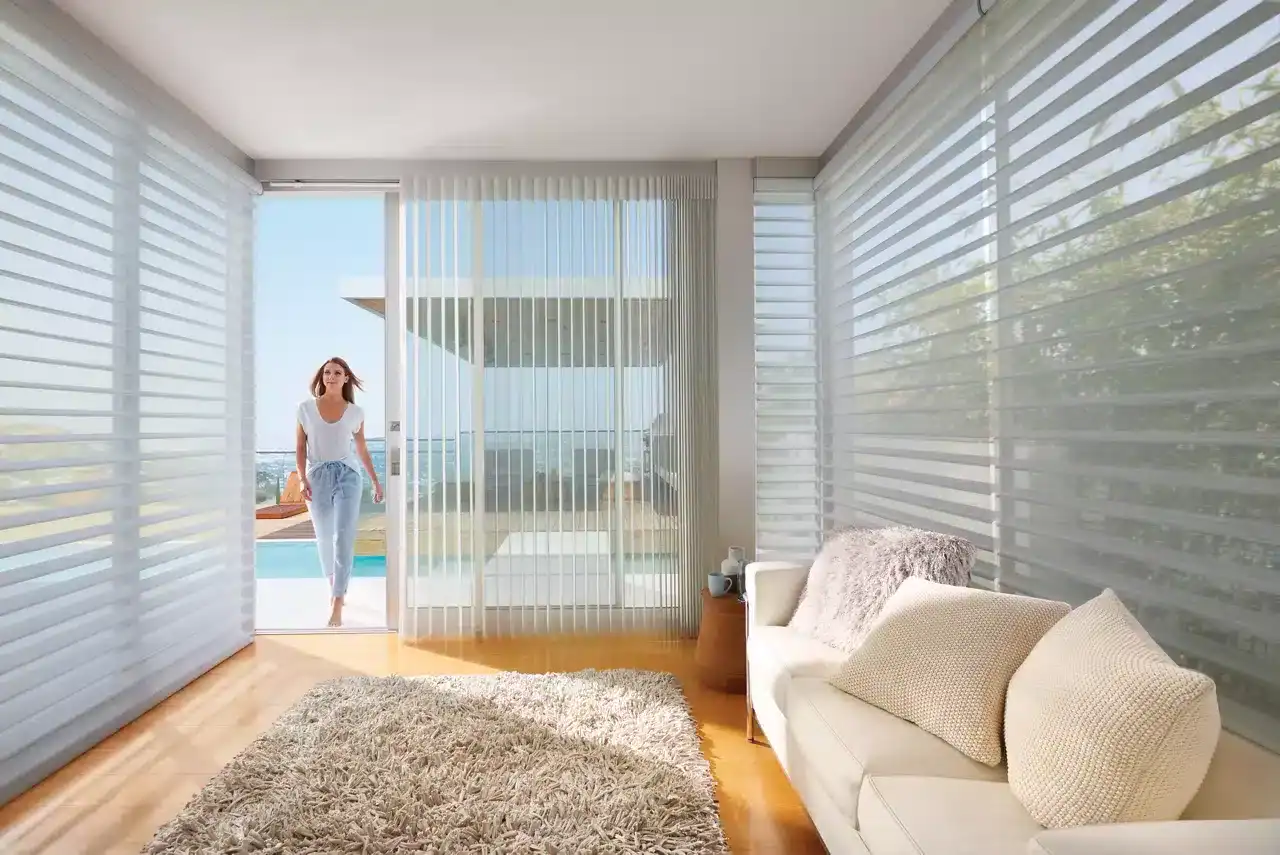 Sunroom with large glass sliding doors, vertical blinds, and cozy beige sofa, offering a bright, airy space with natural light and scenic outdoor views.