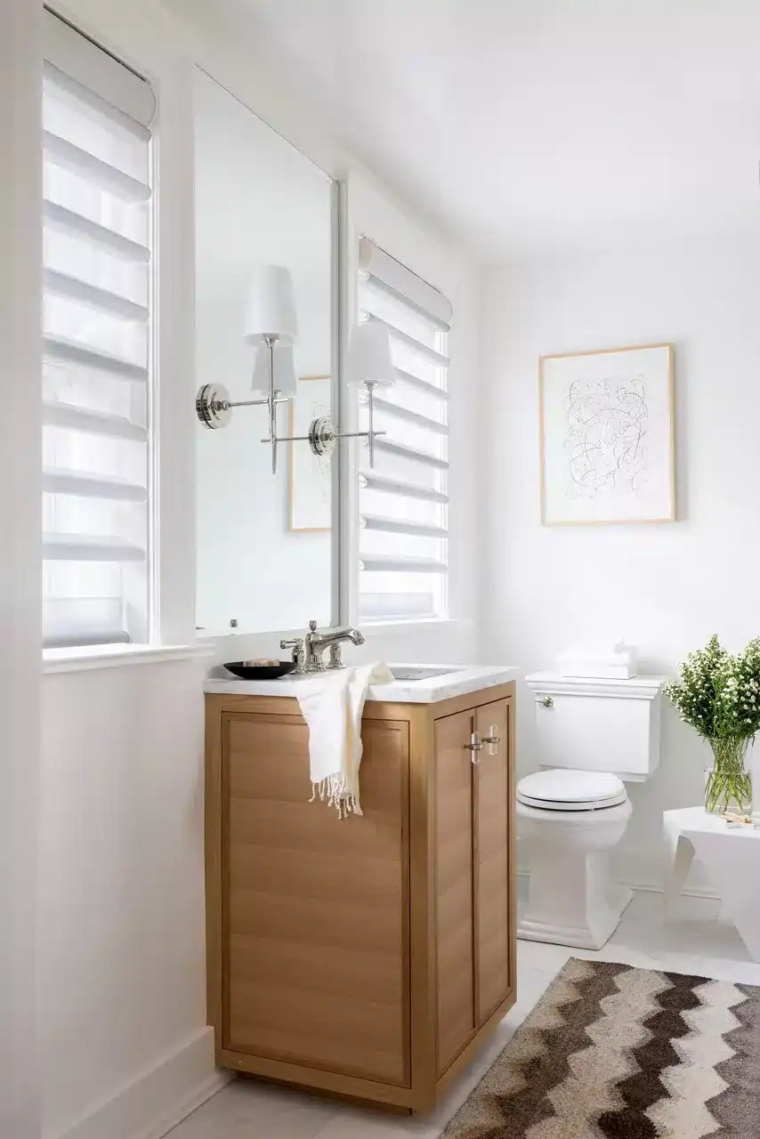 Bright bathroom with wooden vanity, large mirror, white walls, and modern decor elements.