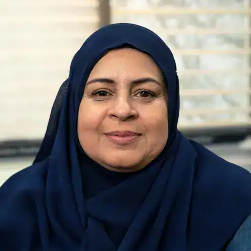 Portrait of Sandi Switzer wearing a navy blue hijab, smiling confidently.