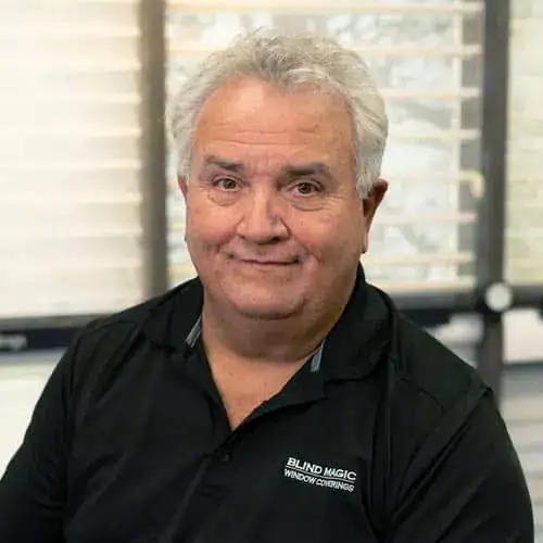 Portrait of Sandi Switzer, a professional in the window covering industry, smiling indoors with a blurred background.