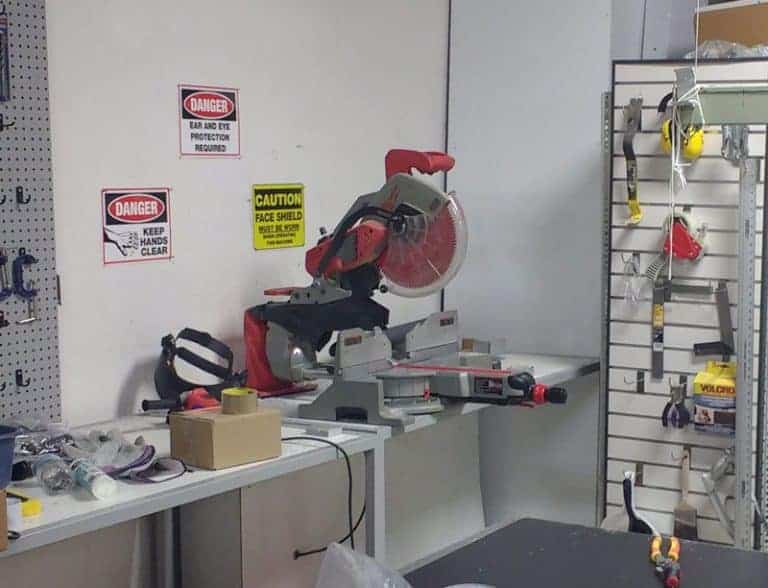 An image of a workshop with tools for blinds repair, including a miter saw and various equipment on a workbench.