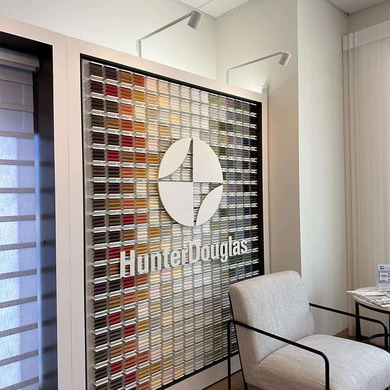Elegant interior with a wall showcasing a variety of paint color samples and the Hunter Douglas logo prominently displayed.