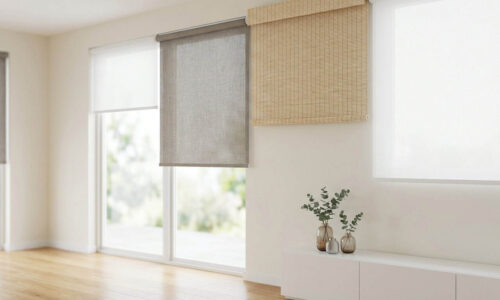 Bright living room with large windows featuring roller blinds in neutral tones, allowing natural light to fill the space. Minimalist decor with a small plant on a white cabinet, creating a calm and ai.