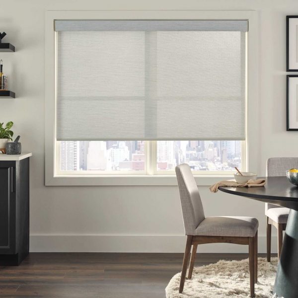 Soft white roller blinds on a large window with a city view, in a modern dining area.