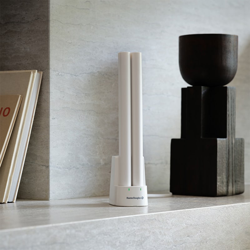 Air purifier on a modern minimalist shelf near decorative black objects and books for home interior design and air quality improvement in living spaces.