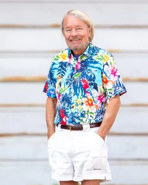 Joe Edwards smiling in his trademark Hawaiian shirt and white shorts.