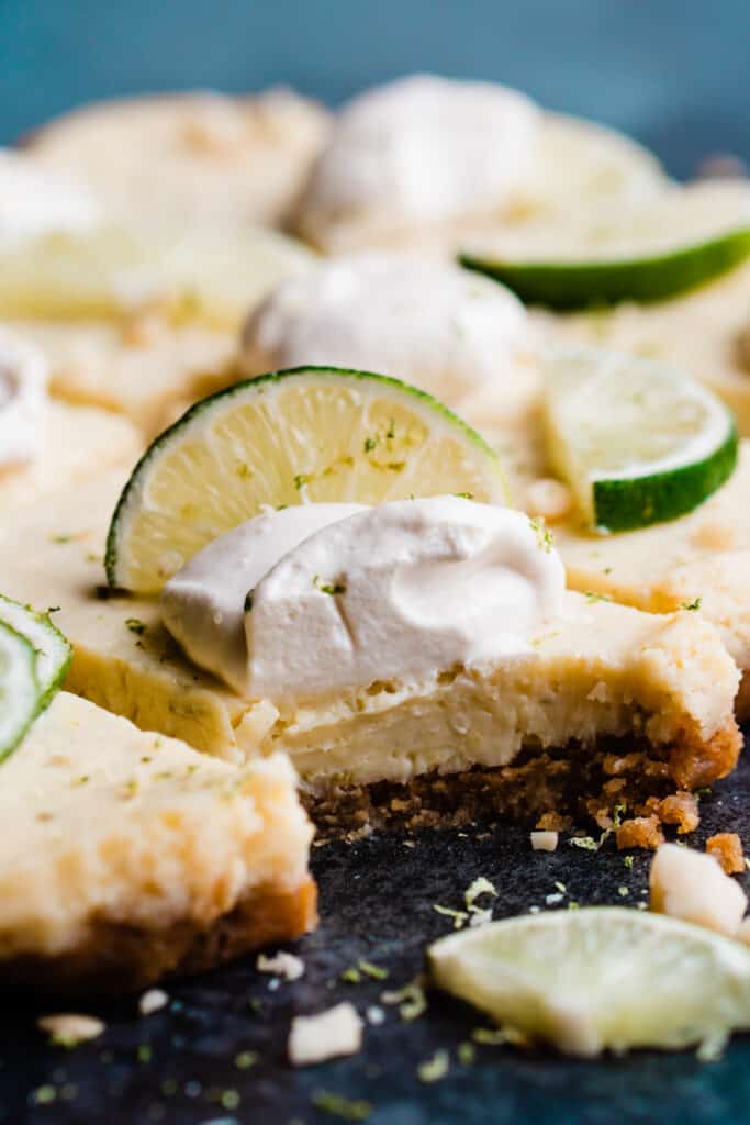 A close-up of a key lime pie bar with a bite taken from the creamy filling and crisp, buttery crust.