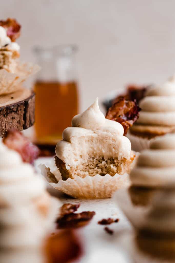 A maple bacon cupcake with a bite taken out of it.