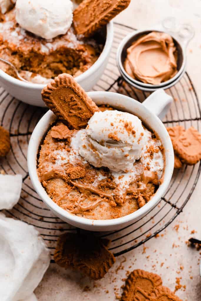 Two cookie butter mug cakes on a vintage wire rack with all the toppings.