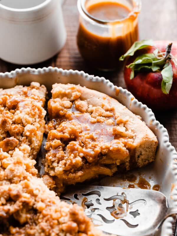 A close-up on a slice of apple pizza in the pie plate, with salted caramel sauce..