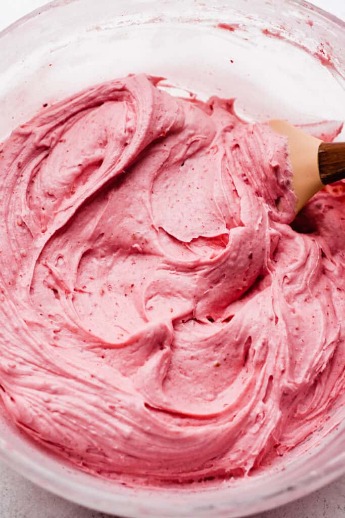 Bright pink raspberry frosting in a bowl.