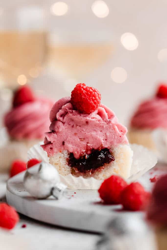 A close-up on a raspberry cupcake cut in half to reveal the raspberry filling.