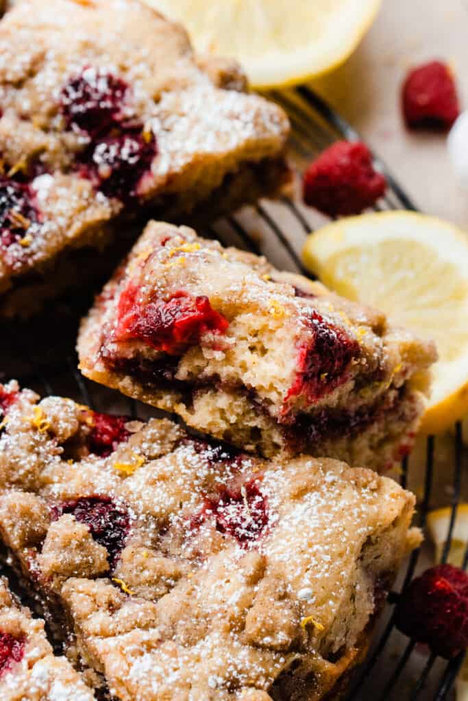 A close-up on a slice of coffee cake with a bite missing, showing the fresh raspberries baked in and the raspberry jam ripple.