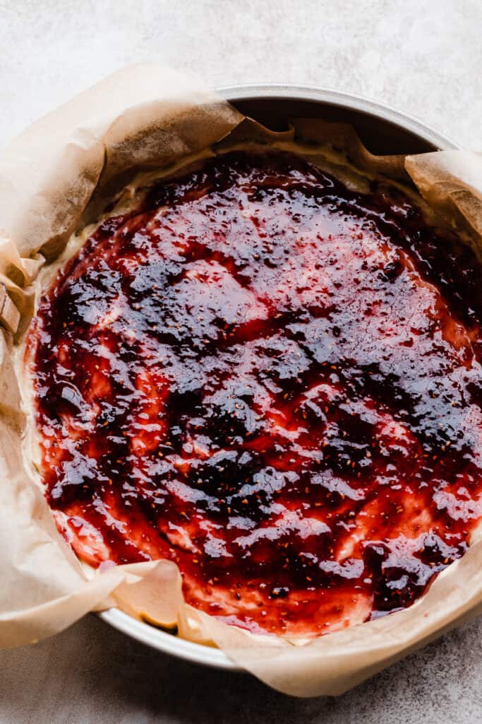 Cake batter topped with raspberry preserves.