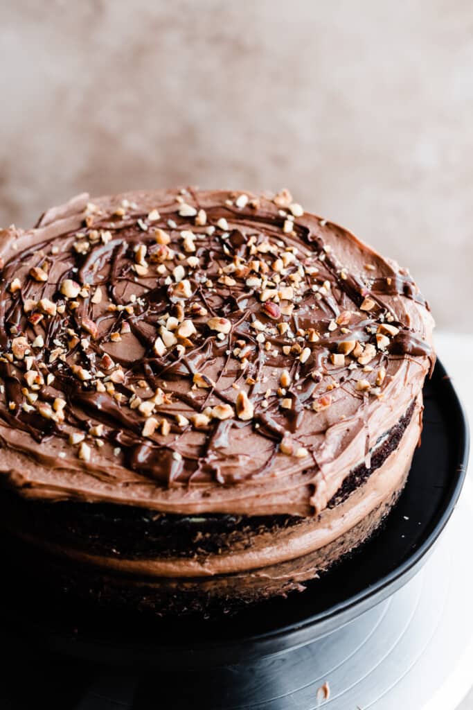 Layers of chocolate cake being frosted with luscious nutella frosting.