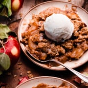 Plates of apple crisp topped with vanilla ice cream.