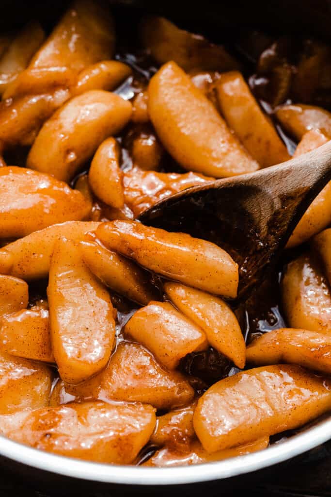 A spoon stirring the apple pie topping.