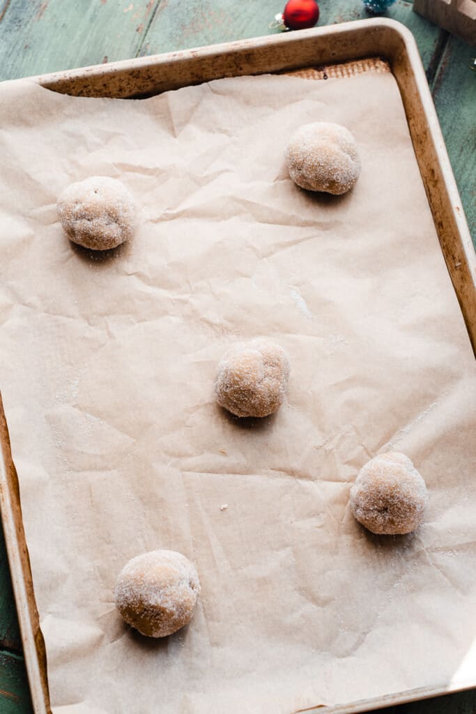 A pan of the cookie dough balls rolled in granulated sugar.