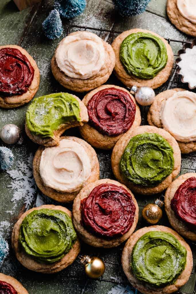 Frosted sour cream cookies on a wire rack, frosted in red, white, and green colors.