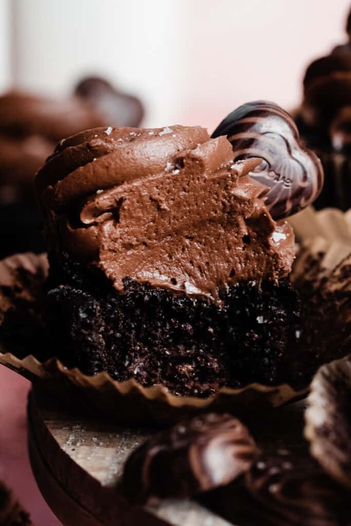 A close-up on a chocolate cupcake, with a bite missing.