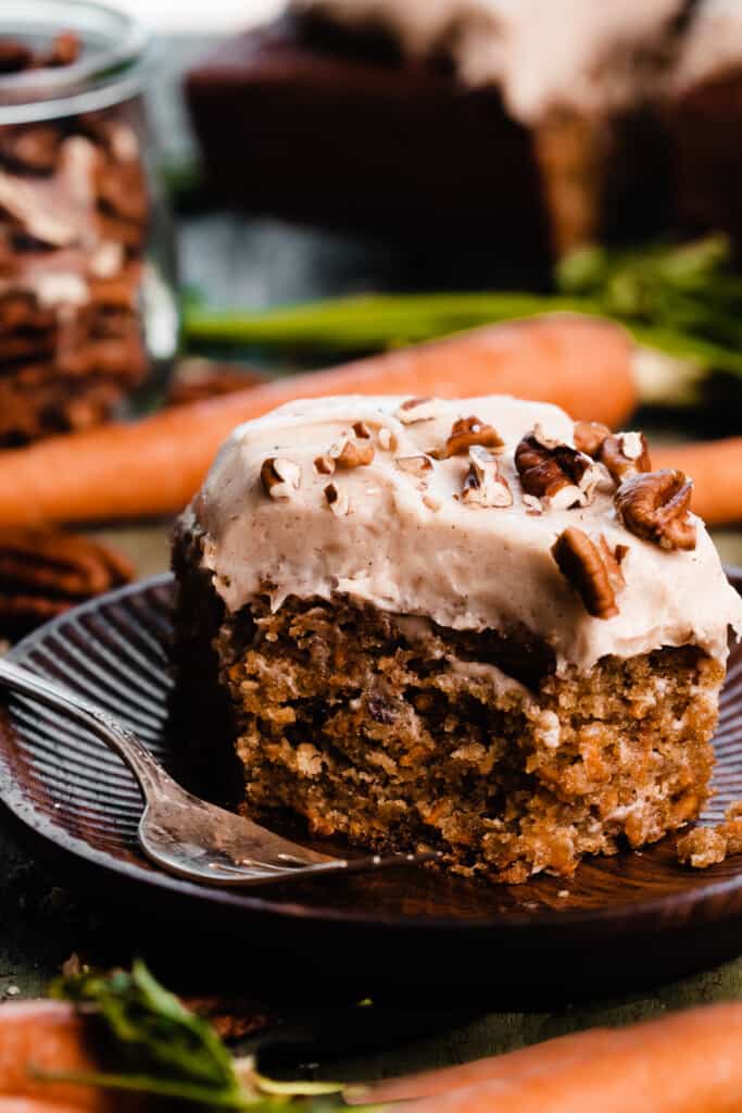A slice of mini carrot cake on a plate, with a bite missing.