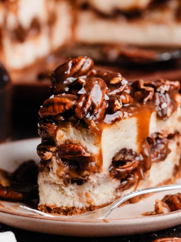 A close-up on a slice of pecan pie cheesecake with a bite missing.