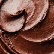 A close-up on swirls of the luscious, shiny chocolate fudge frosting.