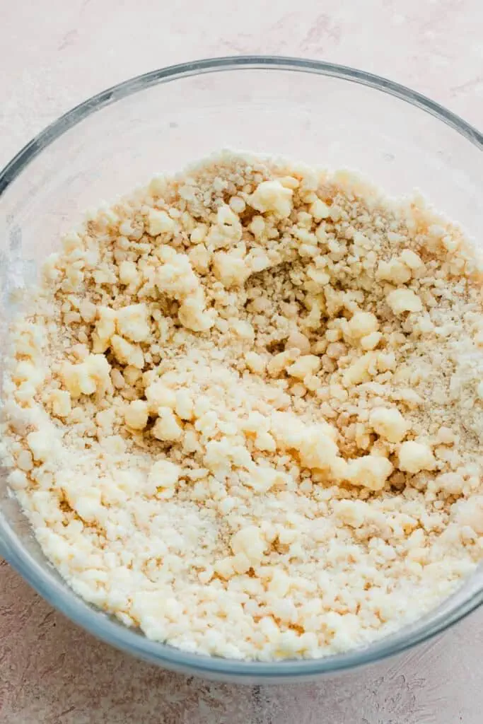 A bowl of the dry ingredients with some small and large clumps from mixing in the butter and oil.