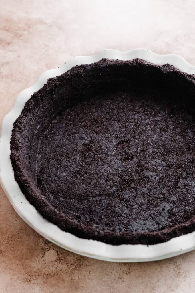The crust mixture pressed into a 9-inch pie dish, ready to be baked.