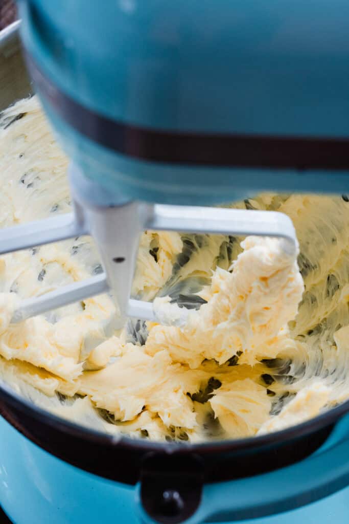 Butter being beaten in the bowl of a stand mixer.