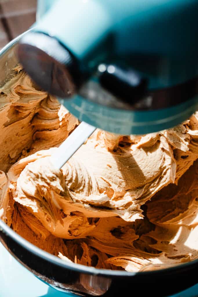 A silky smooth peanut butter frosting in the bowl of a stand mixer.