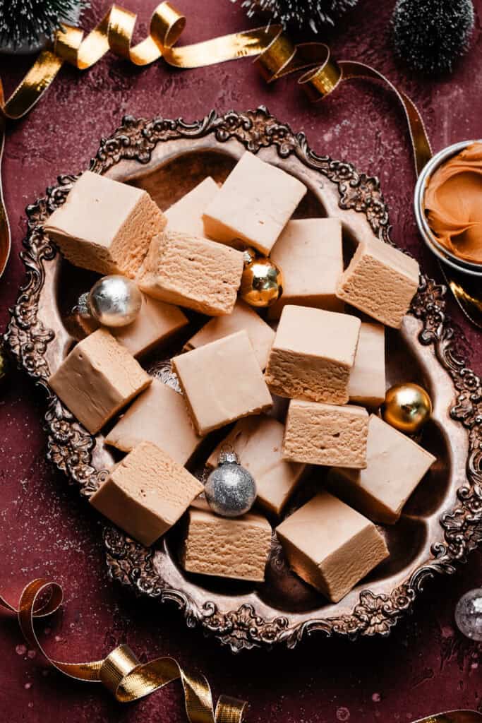 A vintage metal tray full of peanut butter fudge slices on a burgandy backdrop.