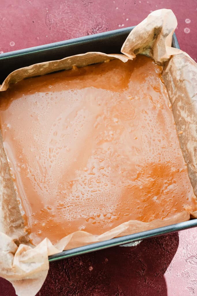 The toffee mixture in a lined 9x9 square pan.
