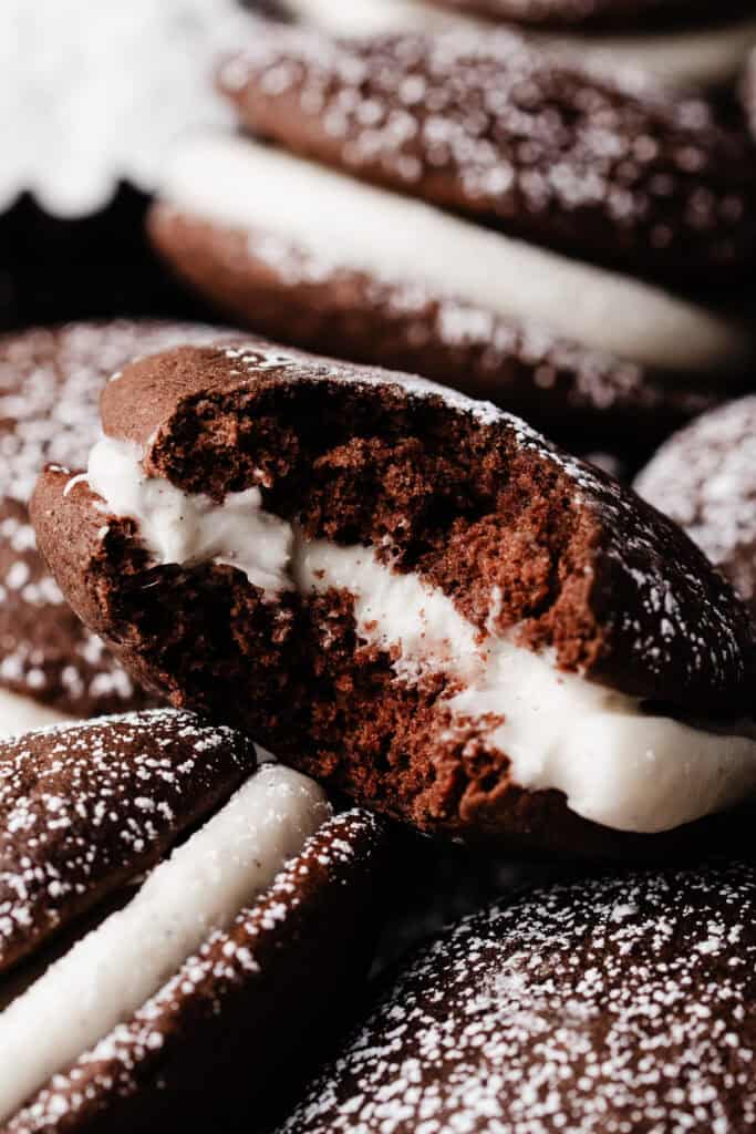 A close-up of a whoopie pie with a bite missing, to show the fluffy texture inside.