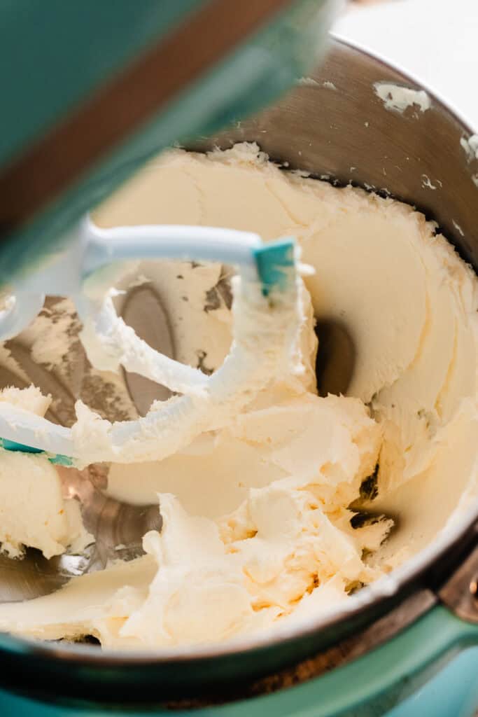 Butter and cream cheese mixed together in the bowl of a stand mixer.